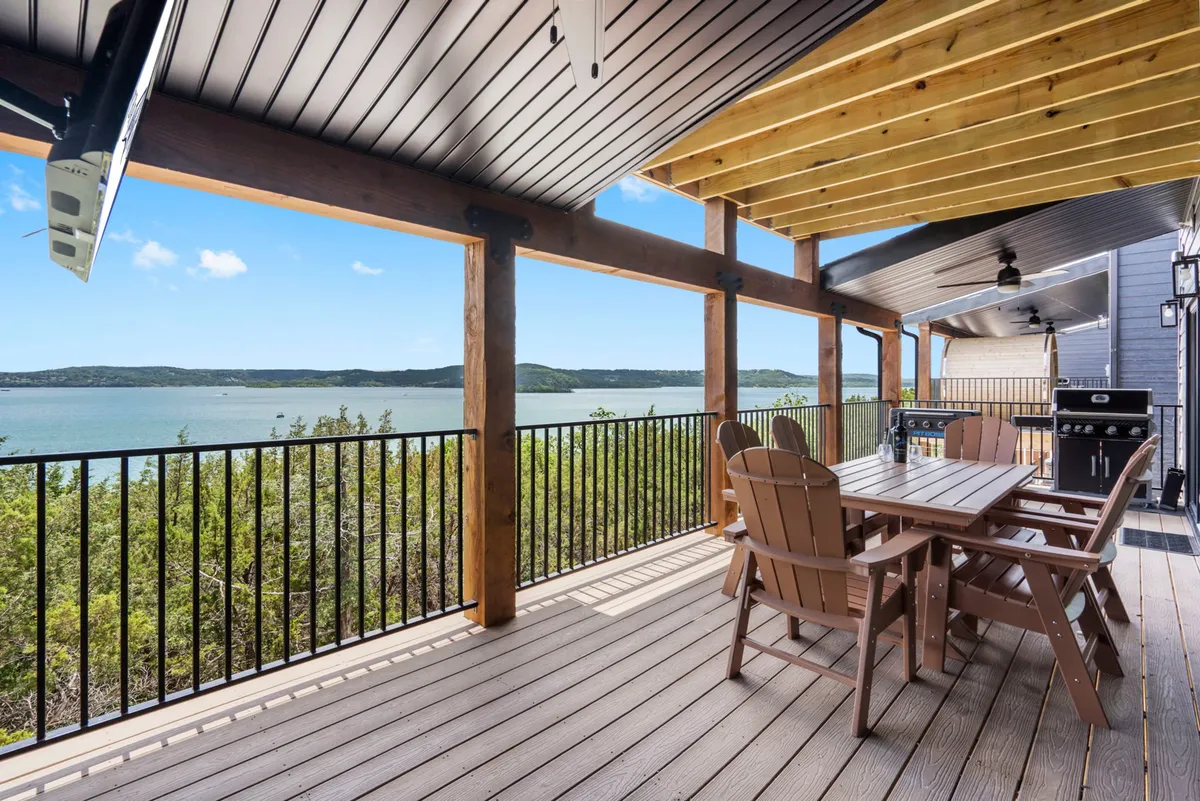 An inviting exterior deck with a dining table, grill area, and sweeping views over the lake. The scene is set for outdoor dining, sunset gatherings, and social relaxation by the water.