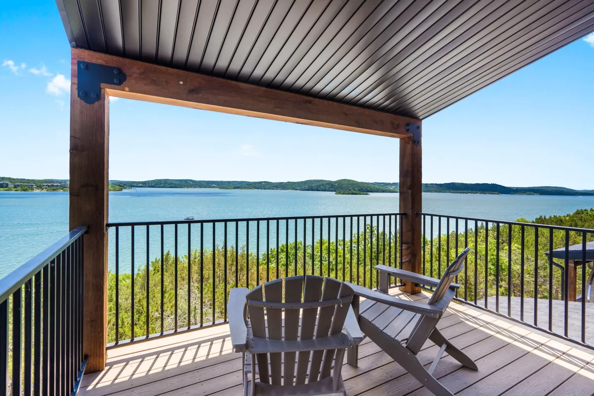 This image presents a serene lakeside view from a wooden deck, complete with Adirondack chairs angled to overlook the tranquil water. The scene is ideal for relaxing, sipping coffee, or soaking in the peaceful sunrise and mist over Table Rock Lake. The presence of the deck gives a sense of private outdoor space directly connected to the natural beauty beyond.
