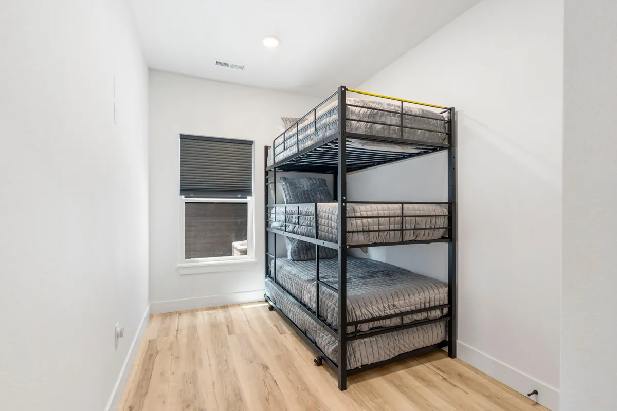 A functional and inviting kids’ bedroom with a sturdy bunk bed placed next to a window. The setup is efficient and cozy, creating a perfect nook for children or groups to rest after a day of adventure.
