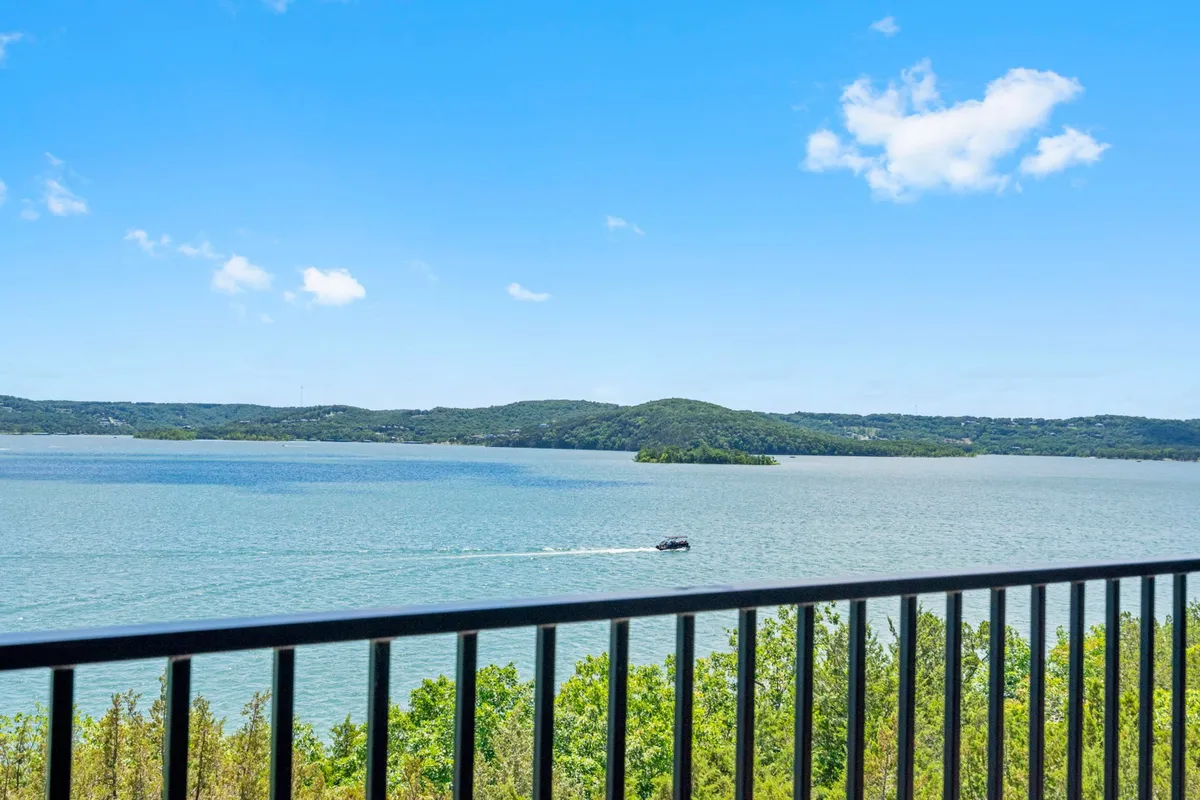 A serene vista over the lake, featuring a boat gliding across the water, distant rolling hills, and an expansive sky. The image captures tranquil moments as well as adventure, reflecting opportunities for boating, fishing, and exploring the outdoors.